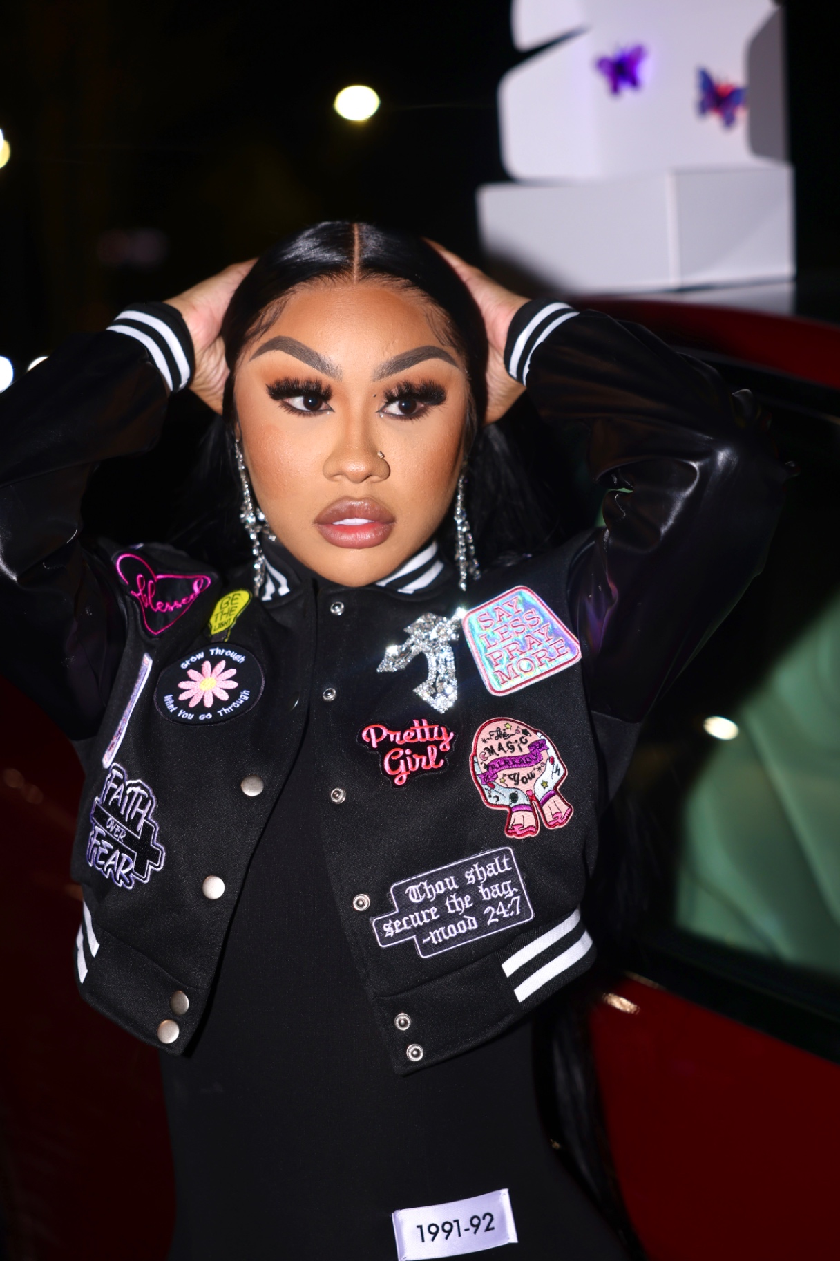 Portrait in a patch-covered varsity jacket at a night event